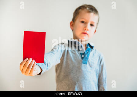 Angry face child showing a red card as a warning, stop bullying concept, blank background. Stock Photo