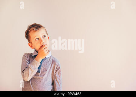 Thoughtful boy with doubts about his ideas, on white background with area copy space. Stock Photo