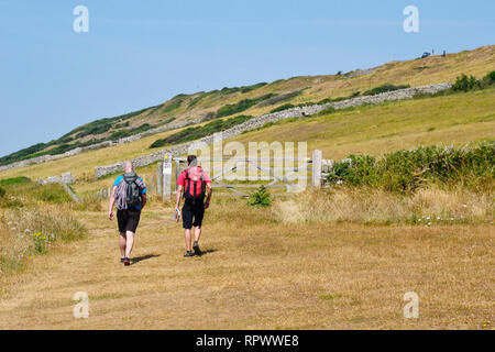 People walking along the coastal path through Durlston Country Park and National Nature Reserve, Swanage, Dorset, UK. Isle of Purbeck Stock Photo