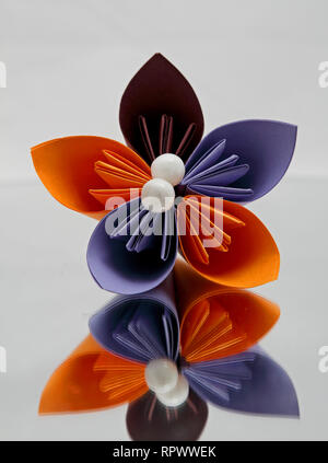Beautiful  colourful origami flower with decoration on a mirror with white background Stock Photo