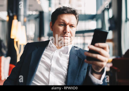 Good looking and stylish young man sitting in a bar during a business break, browsing the internet in his free time. Stock Photo