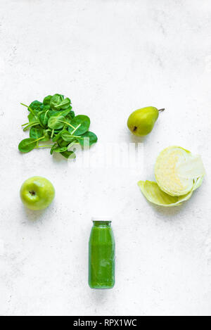 Green smoothie bottle and ingredients (apple, pear, spinach, cabbage) on white background, copy space, top view. Making detox diet vegan healthy smoot Stock Photo