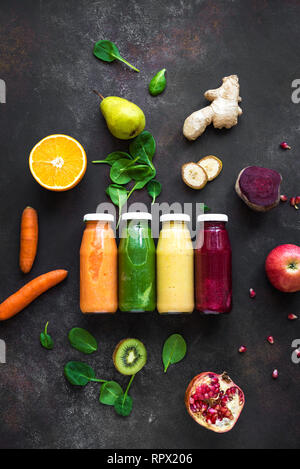 Various colorful smoothies or juices in bottles and ingredients on dark. Healthy diet detox vegan clean food concept, top view.