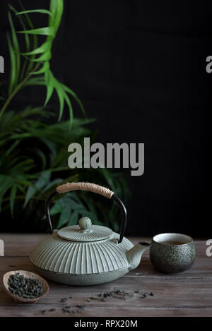 Teapot and Teacups on black background, copy space. Traditional Asian arrangement  for Tea ceremony -  iron teapot and ceramic teacups with tea. Stock Photo