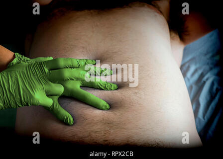 Doctor preparing abdominal palpation in a hospital, conceptual image, horizontal composition Stock Photo