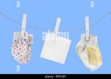 small mittens and socks for newborns on a rope with an empty sign, copyspace, mockup Stock Photo