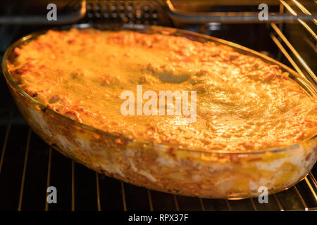 Dish Of Lasagne Cooking Inside Oven. Baking tray with spinach lasagna in oven. Stock Photo