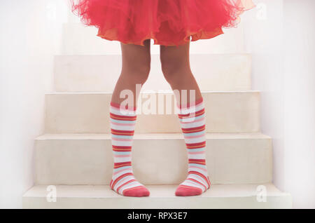 Girl standing on staircase wearing knee high socks and a tutu
