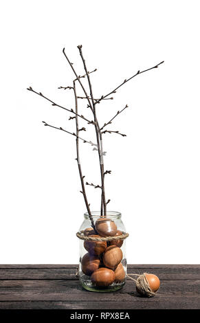 Easter eggs and blooming branches on the light background. Coming spring. Easter concept. Glass jar on wooden desk isolated against white background.  Stock Photo