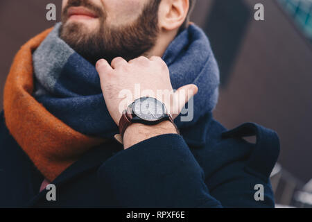 Close up of a fashionable young man's hand fixing a scarf around his neck. Stock Photo
