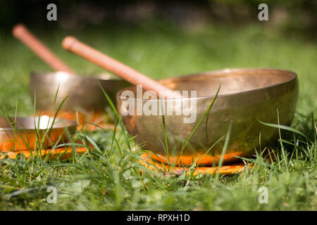 Set of metal singing bowls in the grass of the own garden, zen Stock Photo