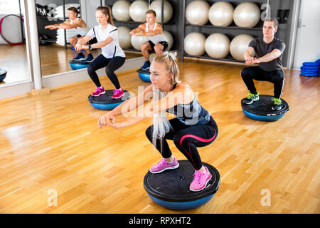 Focused group training squats on half ball at fitness gym Stock Photo