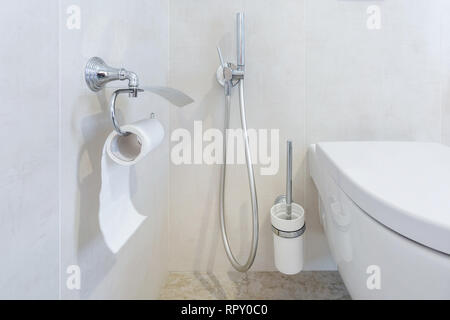 toilet and detail of a corner shower bidet with toilet paper holder on wall mount shower attachment Stock Photo