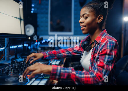 Female sound engineer working at the remote control panel in the recording studio. Musician at the mixer, professional audio mixing Stock Photo
