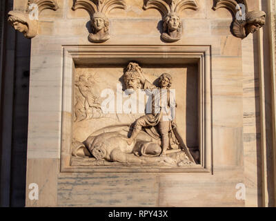 knight with a severed head in his hands bas-relief Artwork on the wall of Milan Cathedral (Duomo) Stock Photo