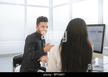 rear view. two employees discuss work issues sitting at the office Desk. Stock Photo