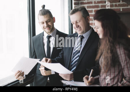 business partners discussing business documents standing in the office. Stock Photo