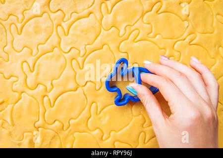 Baking Easter biscuits. Easter symbol concept. Process of cutting rabbit-shaped cookies. Woman holds a mold. Stock Photo