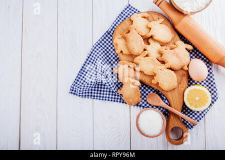 Bunny-shaped cookies with ingredients on wooden background. Recipe of Easter biscuits Stock Photo