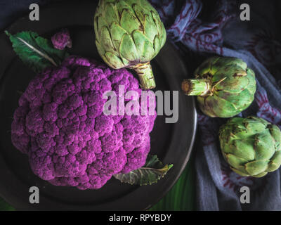 Purple Cauliflower and Three Artichokes Dark Photography Stock Photo