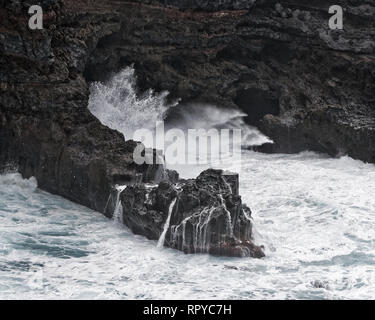 A wave crashes in stormy weather on a rocky coast, spray splashes, water movement in long exposure, detail - Location: Spain, Canary Islands, La Palma Stock Photo