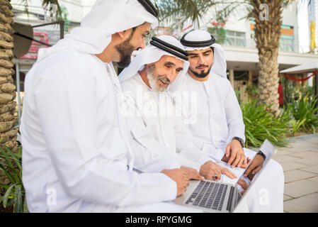 Group of arabian businessmen with kandura meeting outdoors in UAE - Middle-eastern men in Dubai Stock Photo
