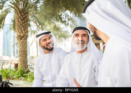 Group of arabian businessmen with kandura meeting outdoors in UAE - Middle-eastern men in Dubai Stock Photo