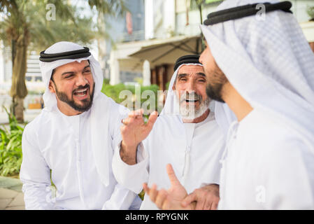 Group of arabian businessmen with kandura meeting outdoors in UAE - Middle-eastern men in Dubai Stock Photo