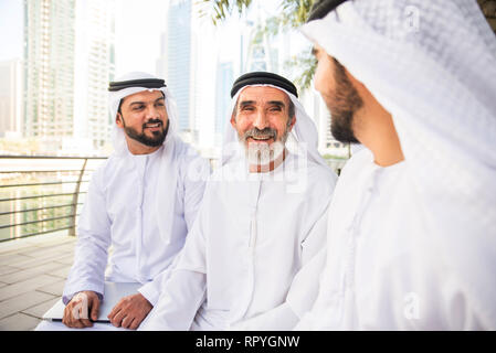 Group of arabian businessmen with kandura meeting outdoors in UAE - Middle-eastern men in Dubai Stock Photo