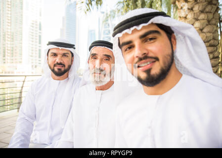 Group of arabian businessmen with kandura meeting outdoors in UAE - Middle-eastern men in Dubai Stock Photo