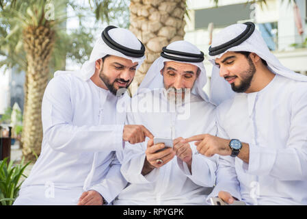 Group of arabian businessmen with kandura meeting outdoors in UAE - Middle-eastern men in Dubai Stock Photo