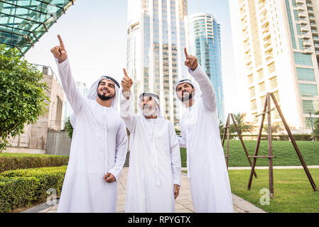 Group of arabian businessmen with kandura meeting outdoors in UAE - Middle-eastern men in Dubai Stock Photo