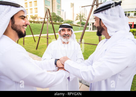 Group of arabian businessmen with kandura meeting outdoors in UAE - Middle-eastern men in Dubai Stock Photo