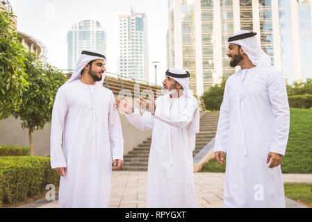 Group of arabian businessmen with kandura meeting outdoors in UAE - Middle-eastern men in Dubai Stock Photo