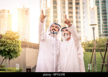 Group of arabian businessmen with kandura meeting outdoors in UAE - Middle-eastern men in Dubai Stock Photo