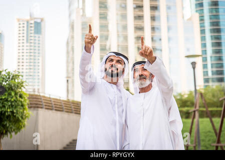 Group of arabian businessmen with kandura meeting outdoors in UAE - Middle-eastern men in Dubai Stock Photo
