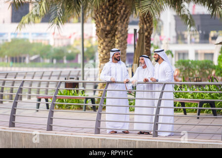Group of arabian businessmen with kandura meeting outdoors in UAE - Middle-eastern men in Dubai Stock Photo