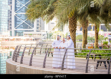 Group of arabian businessmen with kandura meeting outdoors in UAE - Middle-eastern men in Dubai Stock Photo