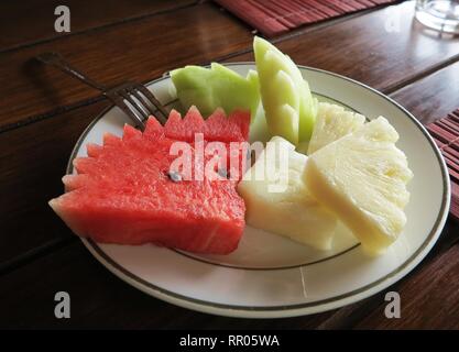 fruits plate with sliced melon,watermelon and pineapple served on the dish with folk Stock Photo
