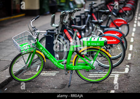 Lime Electric Bike London - a Lime electric hire bike parked next to regular Santander hire bikes in central London UK Stock Photo