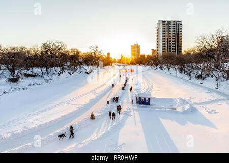 Walkers, hikers and ice skaters on the Assiniboine River Trail at sunset, part of the Red River Mutual Trail, The Forks, Winnipeg, Manitoba, Canada.