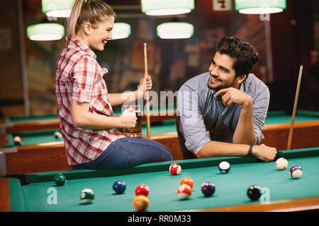billiard playing – smiling couple dating and playing snooker Stock Photo