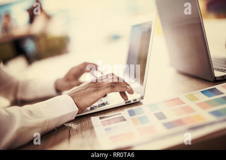 Young modern black muslim business woman wearing a red hijab,working on laptop computer in startup office. Diversity, multiracial concept Stock Photo