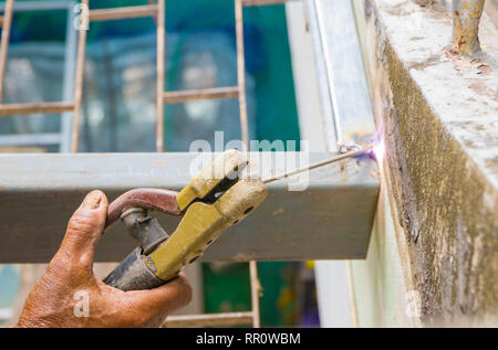 hand hold of elderly welder works steel welding repair on roof high. select focus with shallow depth of field Stock Photo