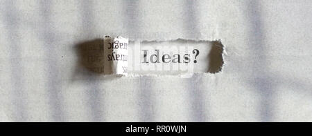 Ideas - word printed on a paper seen through a torn newspaper Stock Photo