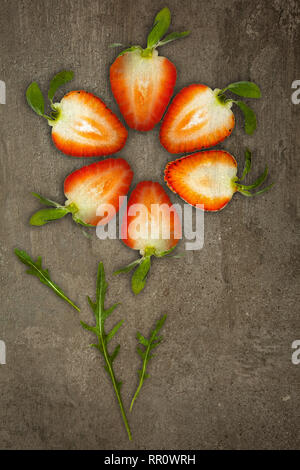 Creative flower made of strawberries cut from below lit on a stone background Food concept Stock Photo