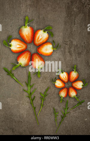 Creative flowers made of strawberries cut from below lit on a stone background Food concept Stock Photo