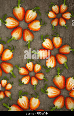 Creative flowers made of strawberries cut from below lit on a stone background Food concept Stock Photo