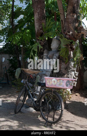 Chiang Rai Thailand, Bicycle and statues in shade of tree at wat ming muang Stock Photo