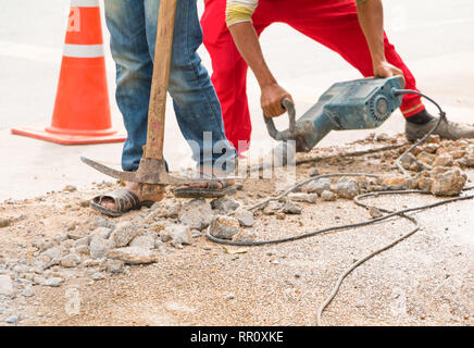 construction drilling repair worker on road surface with heavy duty machine drill motion Stock Photo